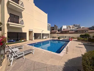 a swimming pool with two chairs next to a building at Frank Porter - Rokane G22 in Dubai