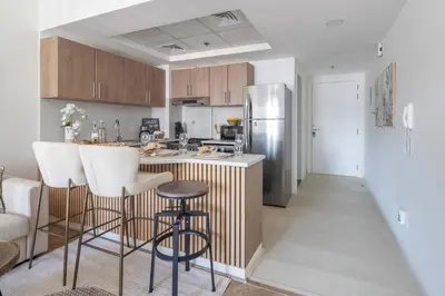 a kitchen with a bar with stools and a refrigerator at Frank Porter - Rokane G22 in Dubai