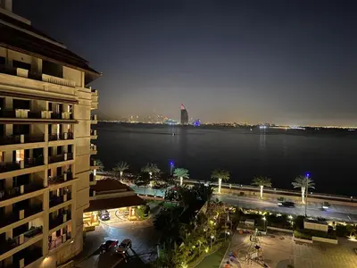 a view of a building and the water at night at Cozy Home with Beach Access in Palm Jumeirah in Dubai