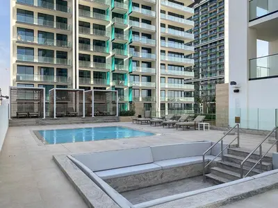 a swimming pool in front of a large building at Silkhaus Classic 1BDR Apartment in Binghatti House in Dubai