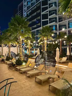 a patio with lounge chairs and palm trees at night at Luxury Studio Apartment in Downtown Dubai in Dubai