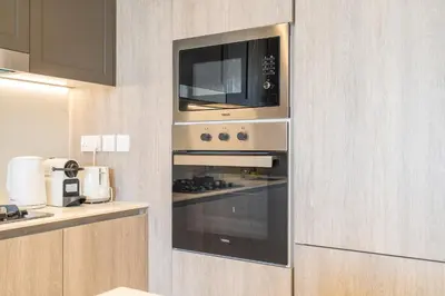 a kitchen with an oven with a microwave at Luxury Stay JVC Modern 1BHK Pool & Gym Access in Dubai