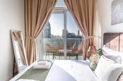 a bedroom with a bed and a balcony with a table at Full burj khalifa view 1bhk app in Dubai