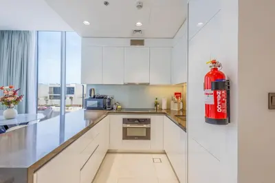 a large white kitchen with a red fire extinguisher at Charming 1 Bedroom Apt in MBR - Near Downtown Dubai in Dubai