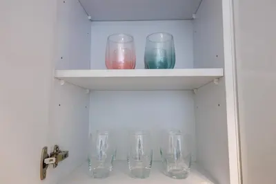 a row of glass cups sitting on a shelf at Charming 1 Bedroom Apt in MBR - Near Downtown Dubai in Dubai