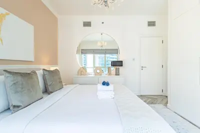 a white bedroom with a large white bed at Serene 2BR Escape - Al Majara - Waterfront Stay in Dubai