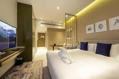 a bedroom with a large white bed and a flat screen tv at Stylish Studio Apartment with pool in Business Bay in Dubai