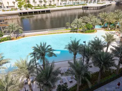 an overhead view of a large swimming pool with palm trees at Sunset Creek Harbour, Dubai in Dubai