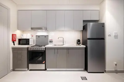 a kitchen with white cabinets and a stainless steel refrigerator at FORTE Tower 2 - One-Bedroom Apartment in DOWNTOWN Dubai, near Burj Khalifa & Dubai Fountains - Apartment in Forte Tower 2 in Dubai
