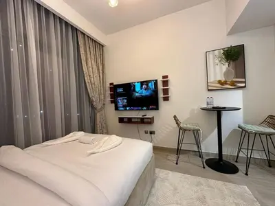 a hotel room with a bed and a flat screen tv at Studio Designer Azizi 41 in Dubai