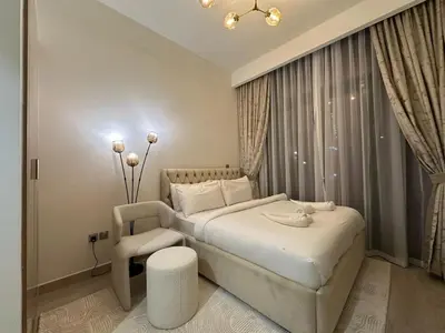 a bedroom with a white bed and a chair at Studio Designer Azizi 41 in Dubai