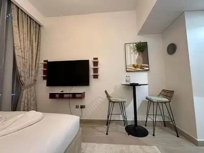 a bedroom with a bed and two chairs and a tv at Studio Designer Azizi 41 in Dubai