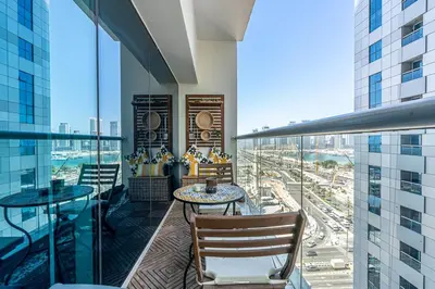 a balcony with tables and chairs and a view of a city at Spacious 2 BR With Pool, Gym and Kid's Playground in Dubai