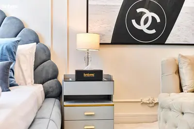 a bedroom with a couch and a table with a lamp at bnbmehomes - Oxford Terraces in Dubai