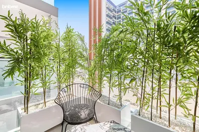 a balcony with a table and chairs and trees at bnbmehomes - Oxford Terraces in Dubai