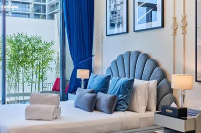 a bedroom with a bed with a blue headboard and pillows at bnbmehomes - Oxford Terraces in Dubai