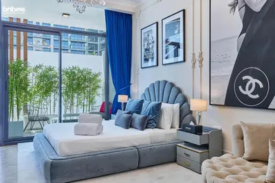 a bedroom with a large bed and a chair at bnbmehomes - Oxford Terraces in Dubai