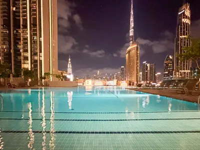 a large swimming pool in a city at night at Elite 4 Bedroom Luxury Apartment, Burj Khalifa View, Opposite Dubai Mall, Infinity Swimming Pool in Dubai