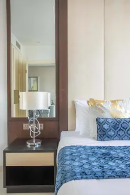 a bedroom with a bed with a lamp and a mirror at Frank Porter - Damac Distinction in Dubai