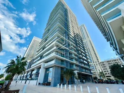 a tall building with palm trees in front of it at Gorgeous 1BD Apt with beach access in Grand Bleu in Dubai