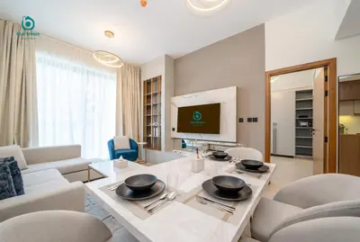 a living room with a table and chairs and a television at Blue Breeze - Chic & Cozy 1 BR Getaway in Al Furjan in Dubai