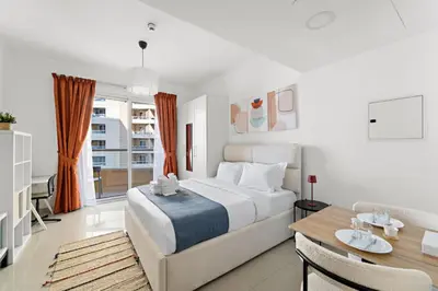 a bedroom with a large bed and a dining table at Modern Studio in Production City in Dubai