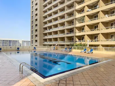 a large swimming pool in front of a building at Modern Studio in Production City in Dubai