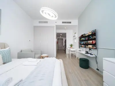 a white bedroom with a large bed and a living room at Elegant Studio in Bloom JVC with High-End Finishes in Dubai