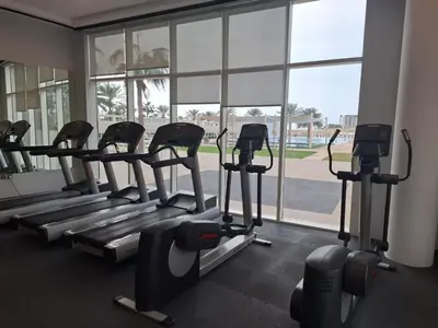 a gym with several tread machines in front of a window at Al Bateen - Two Bedroom in JBR with City Views in Dubai