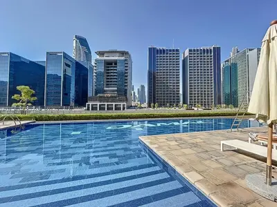 a swimming pool with a city skyline in the background at Reva Residences - Cosy One Bedroom in Business Bay in Dubai