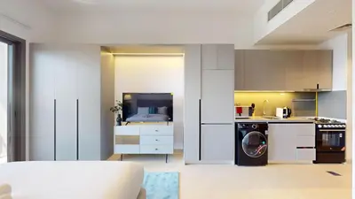 a kitchen with white cabinets and a washer and dryer at Mag 980 - Cosy Studio with City Views in Meydan in Dubai