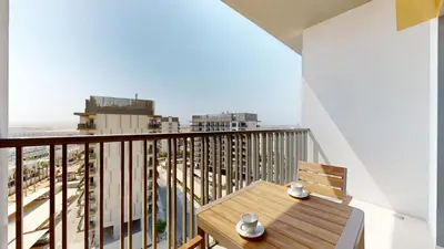 a balcony with a wooden table and a view of a city at Mag 980 - Cosy Studio with City Views in Meydan in Dubai