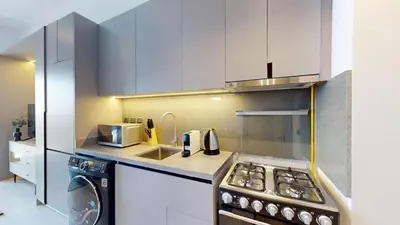 a kitchen with white cabinets and a stove top oven at Mag 980 - Cosy Studio with City Views in Meydan in Dubai