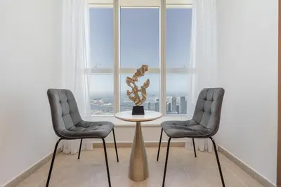 two chairs and a table in front of a window at Stylish1BHK in Elite Residences, Marina with View in Dubai