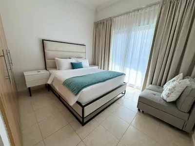 a bedroom with a bed and a chair and a window at Holiday Homes by DO- The Zumrud in Dubai