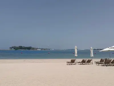 a group of chairs and umbrellas on a beach at Bright 2 Bedroom Apartment, Beach & Pool Access in Dubai
