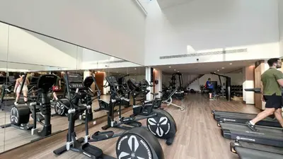 a gym with a bunch of treadmills and a man walking in the gym at 1-Bedroom Apartment with Greenery & City Views in The Terraces in Dubai