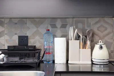 a kitchen counter with utensils and a bottle of water at 1-Bedroom Apartment with Greenery & City Views in The Terraces in Dubai