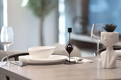 a table with a plate and two wine glasses at 1-Bedroom Apartment with Greenery & City Views in The Terraces in Dubai