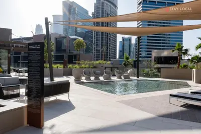 a pool on the roof of a building with chairs at Relax in Style with Outdoor Pool and Burj Khalifa Views Nearby in Dubai