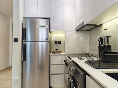a stainless steel refrigerator in a kitchen with white cabinets at Modern Luxury Fully Furnished 1BH Apartment in Binghatt Nova JVC - Easy Access to JBR, Circle Mall & Dubai Hills Mall in Dubai