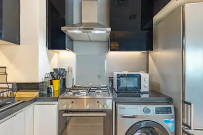 a kitchen with a stove and a microwave at Spacious 1BR - Balcony & Pool View - Capital Bay in Dubai