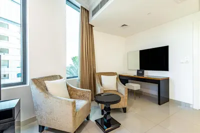 a hotel room with two chairs and a desk and a tv at Spacious 1BR - Balcony & Pool View - Capital Bay in Dubai