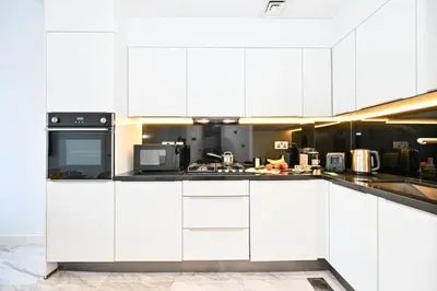 a white kitchen with white cabinets and appliances at The Pad Burj Khalifa view 1Bd in Dubai
