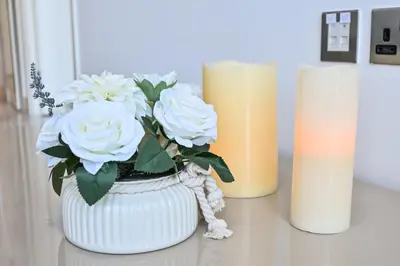 a white vase with flowers on a table next to two candles at The Pad Burj Khalifa view 1Bd in Dubai
