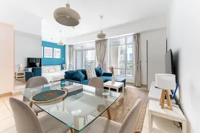 a living room with a glass table and a blue couch at HAVN - Studio in Downtown, 10mins to Dubai Mall in Dubai