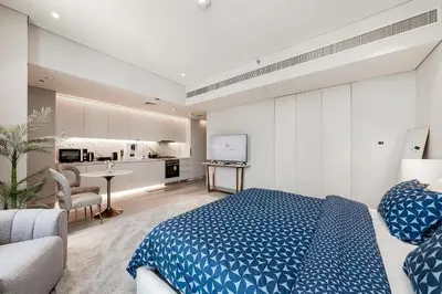 a bedroom with a blue bed and a kitchen at Great Apartments at Marina Star with City View in Dubai