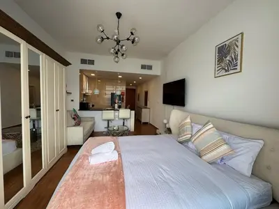 a bedroom with a large bed and a living room at Cozy Studio Apartment Holiday Home l Perfect for Couples in Dubai