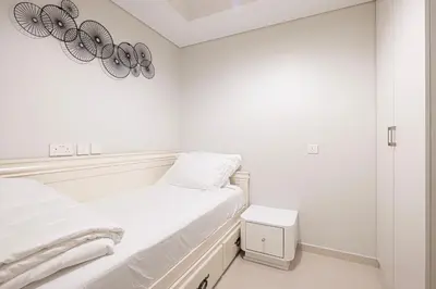 a white bedroom with a bed and a mirror at UrbanHomes - Luxury and Cozy 3BDR Apartment in Business Bay Canal View in Dubai