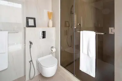 a bathroom with a shower and a toilet and a glass door at Frank Porter - Peninsula Five in Dubai